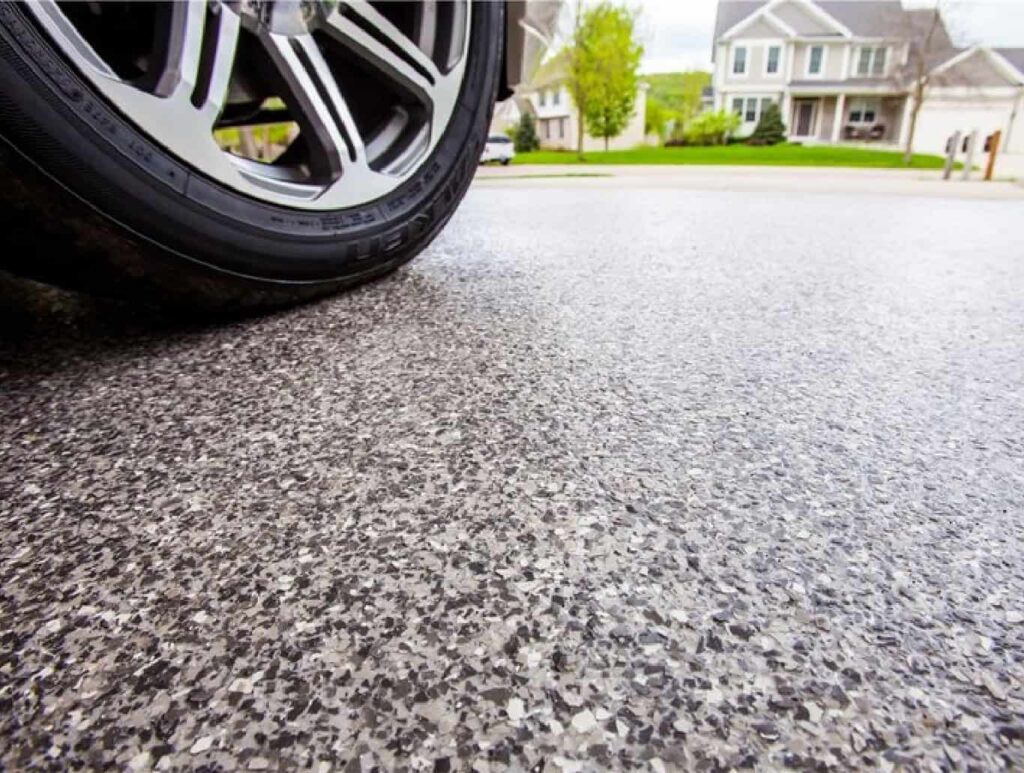 A close up view of a tire on a fresh concrete driveway coating in Texas.