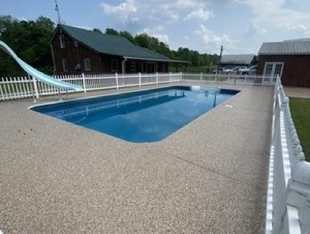 A beautiful pool deck coating in Texas from the team at Deluxe Garages with a slide and pool house.